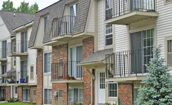 An apartment building with balconies and brick and white siding